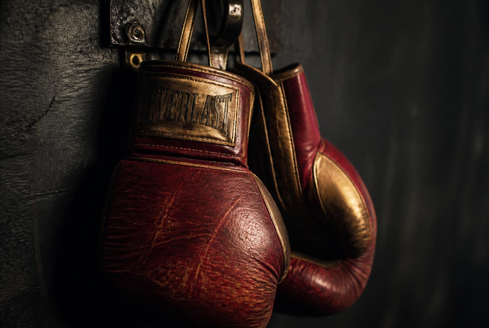 Worn boxing gloves hanging on a hook