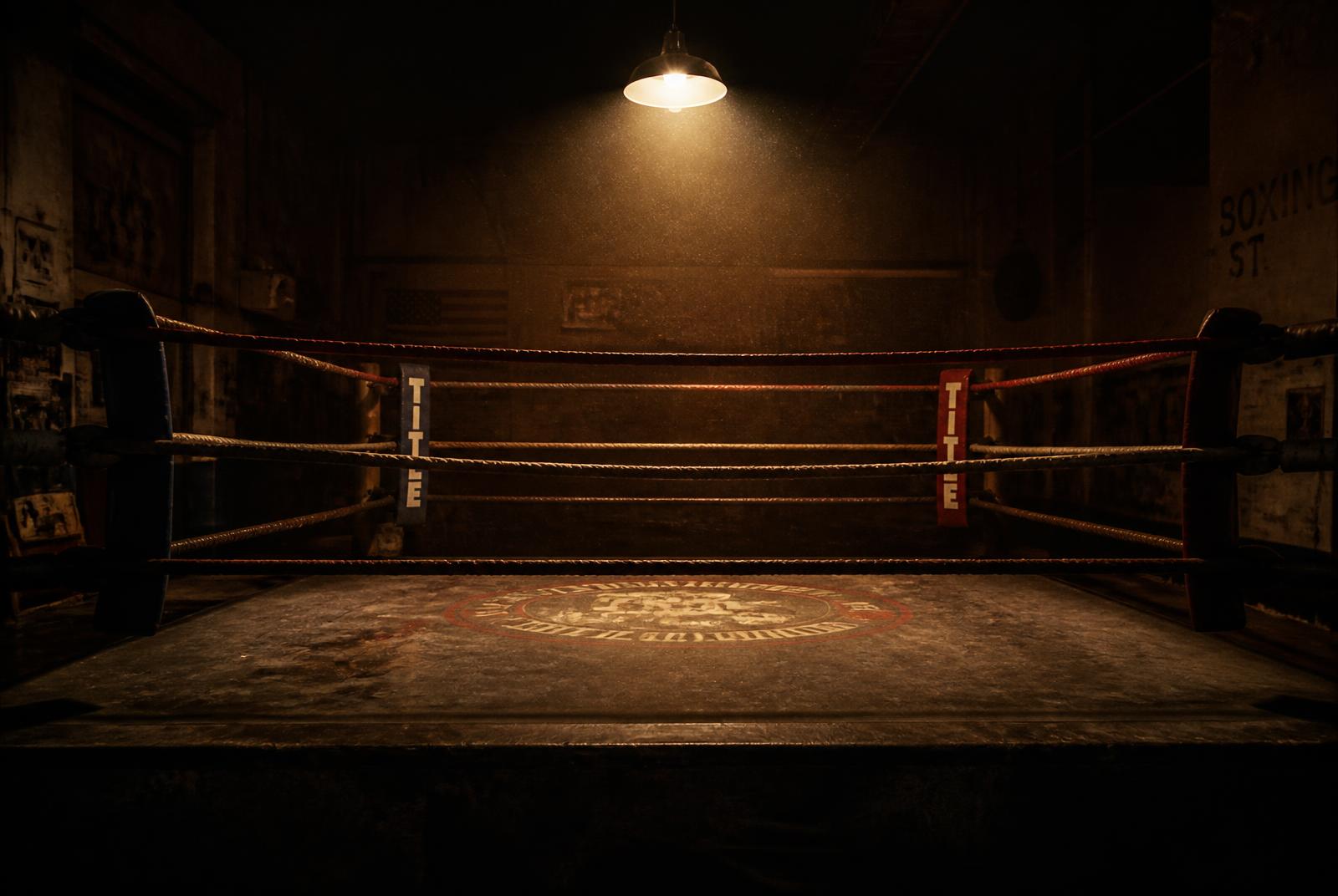 An empty boxing ring lit by a single overhead lamp